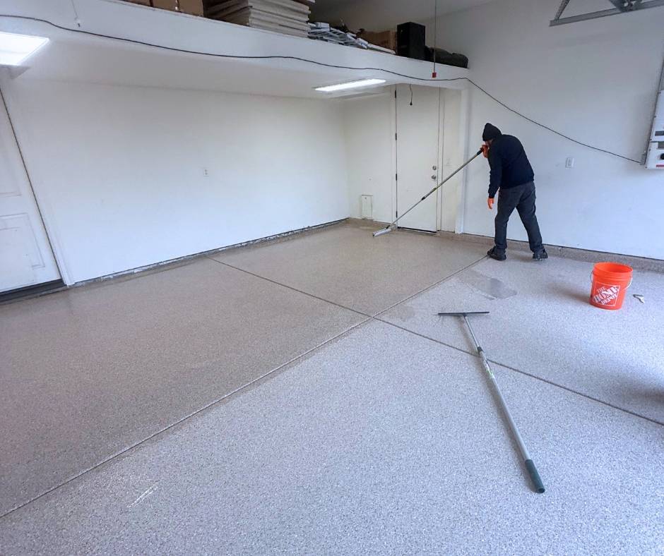 TRICO PAINTING applying a clear polyaspartic top coat over an epoxy flake garage floor to protect and seal the surface in a Roseville, California home.