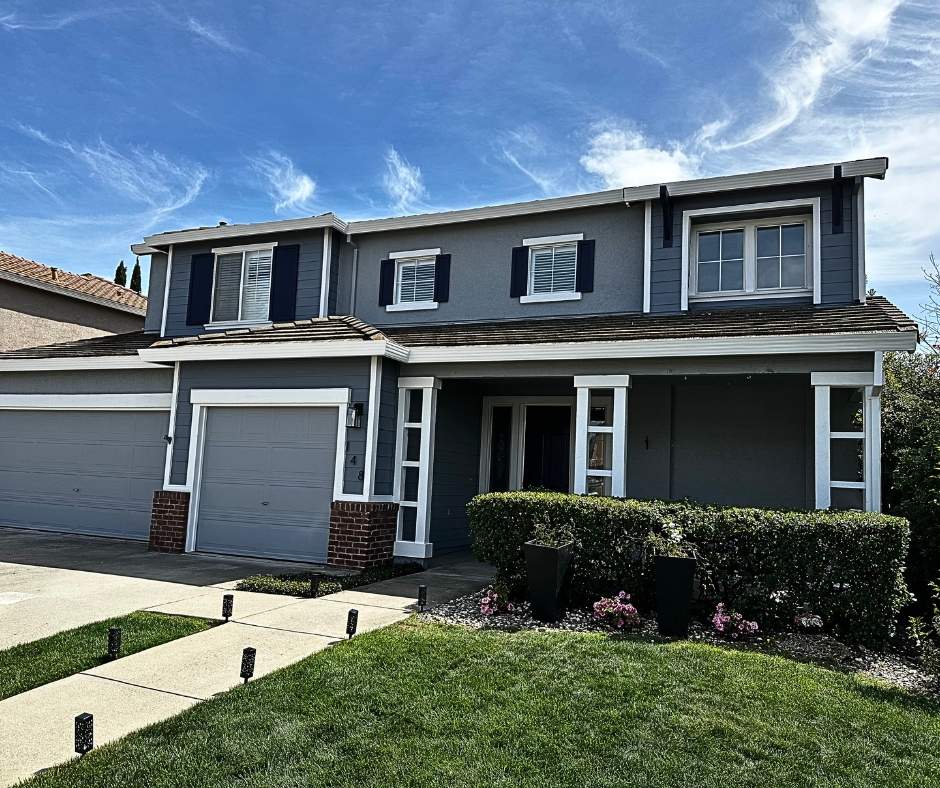 Blue-gray exterior house painted by Trico Painting with white trim and black shutters (2026 exterior color trend)